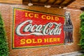 Classic trademark branding logo of CoCa-Cola on red brick wall.